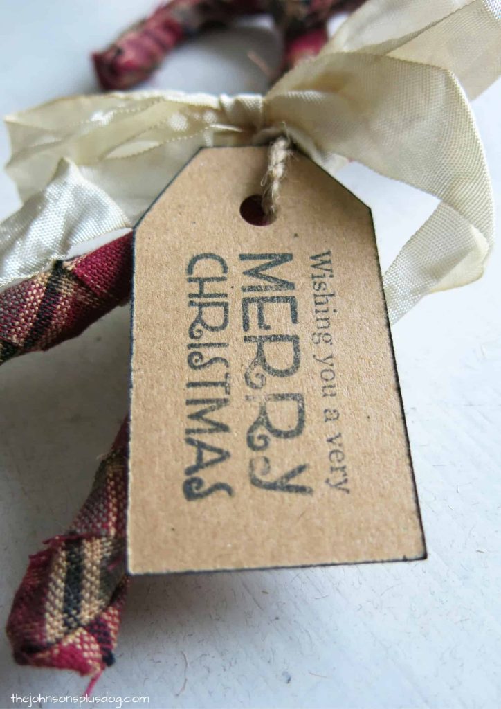 A close up look at the decorative Christmas gift tag tied around the homemade fabric candy cane ornaments.