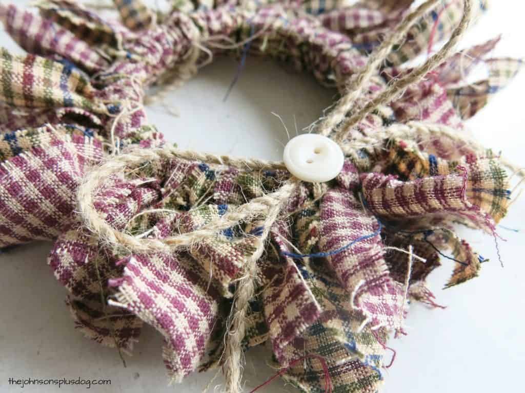 Add a cute jute twine bow and button to the top of this homemade fabric ornament, made with strips of homespun fabric.