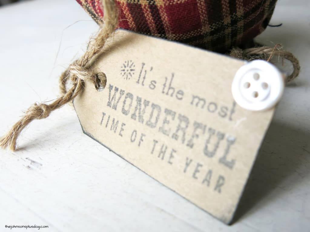 A stamped gift tag attached to the homemade fabric ornament, decorated with a single button.