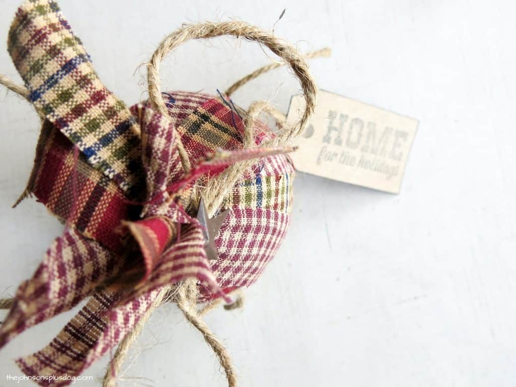 An overhead look of our first completed homemade fabric ornament - a round ornament made with various plaid pieces of homespun fabric.