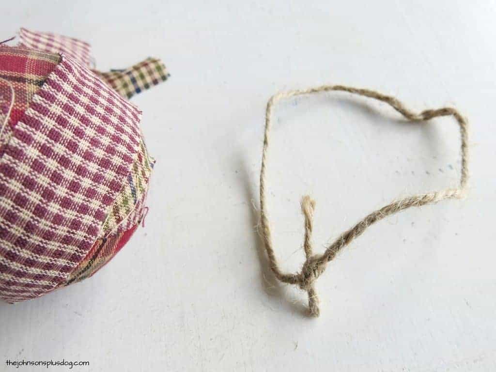 A piece of jute twine tied in a loop, sitting next to a homemade fabric ornament.