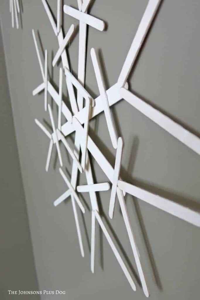 Side view of popsicle sticks snowflake attached to the gray wall