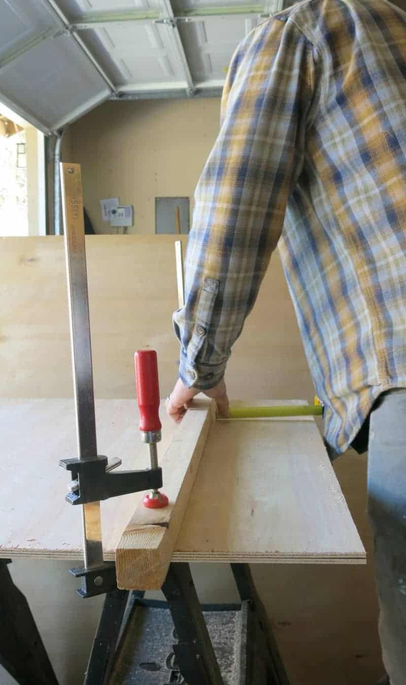 To cut shiplap wood without a table saw, you measure plywood with a guide board that's clamped down, preparing to cut the shiplap using a skill saw.