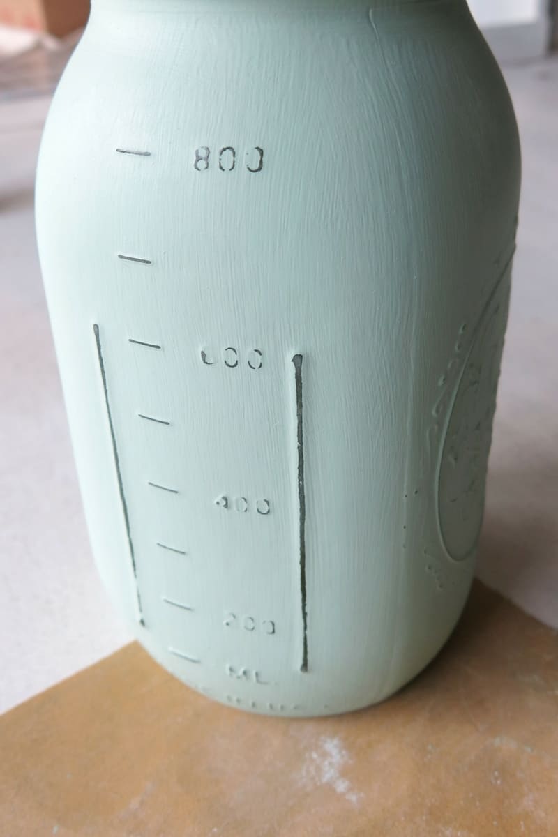 Photo of mint green painted mason jar with raised numbers worn off from being distressed with sandpaper 