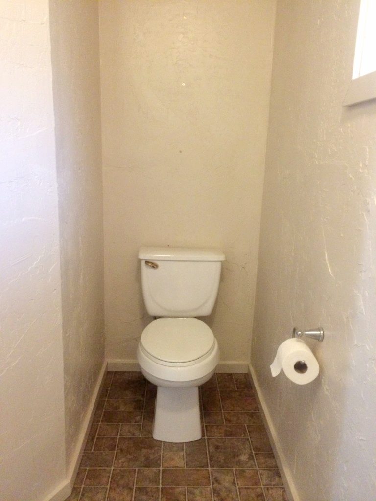 Photo of small bathroom with toilet in a small alcove with tan wall paint