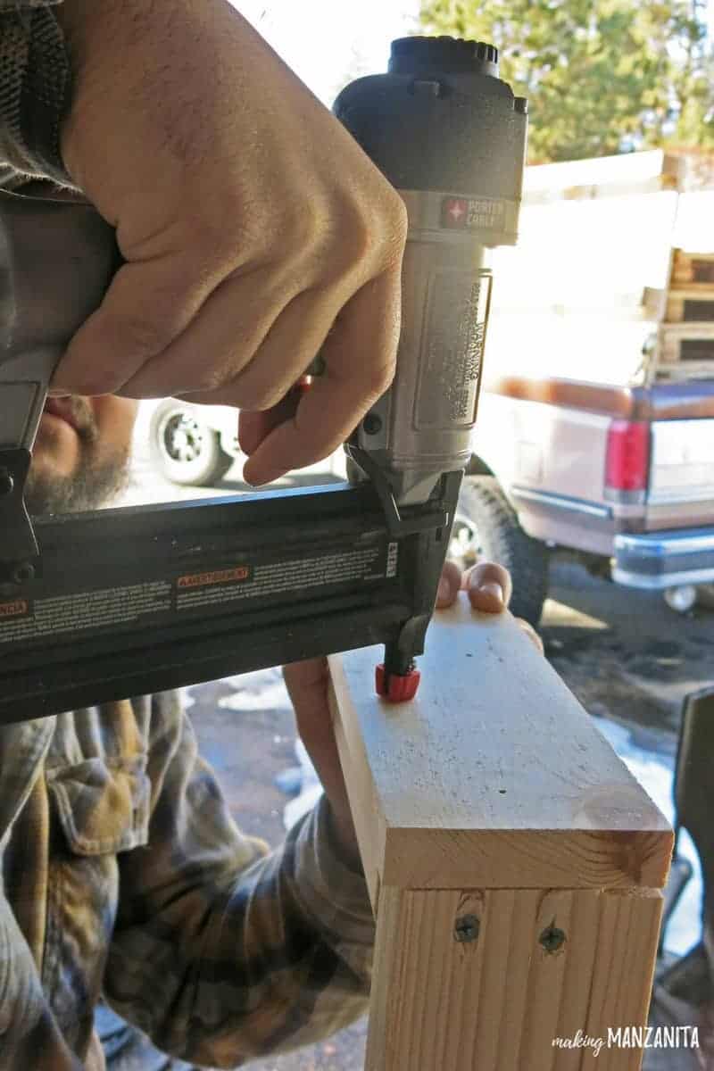 Man nailing boards onto 2x4s with nail gun