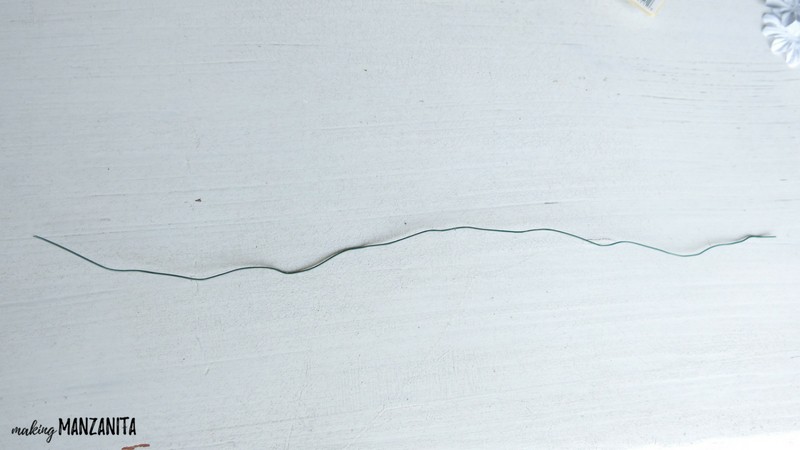 A single piece of floral wire sits on a white table.