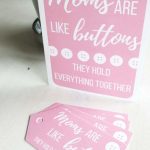 Free printable Mother's Day card sitting on white table that says moms are like buttons they hold everything together with 4 printed gift tags sitting in front of the card