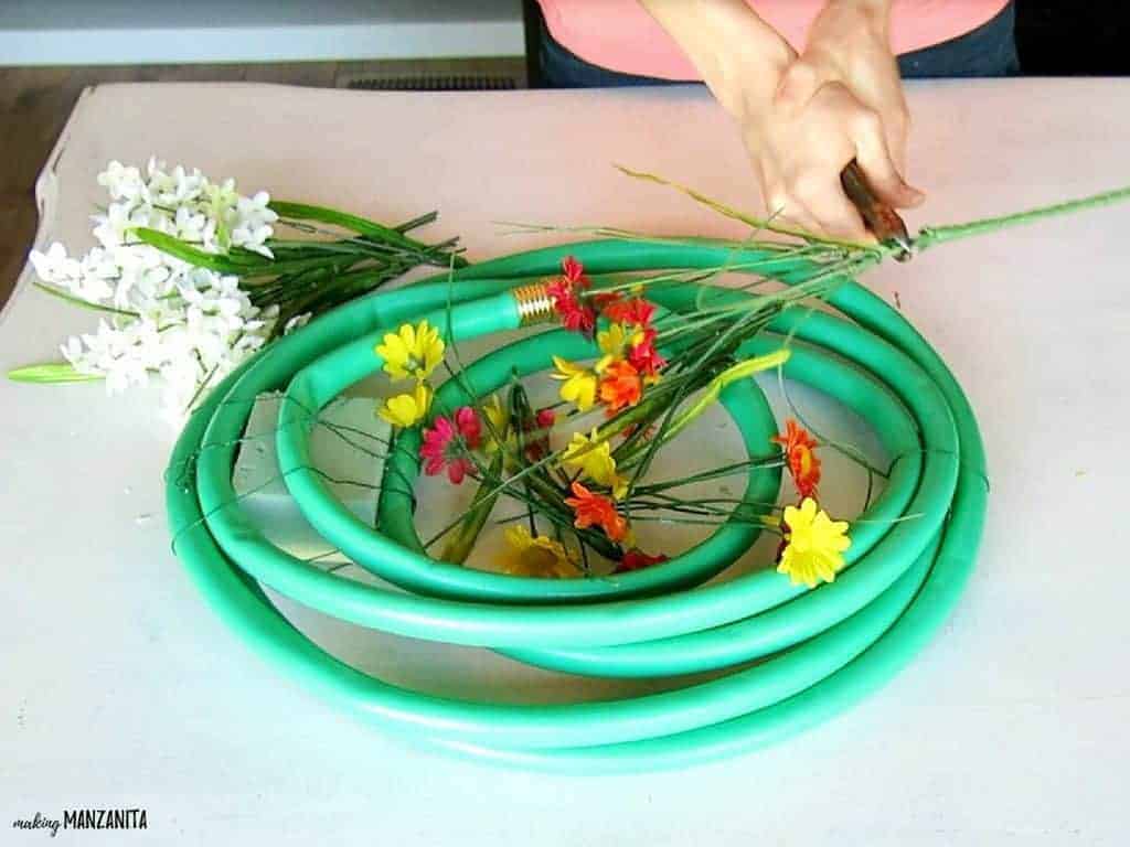 A woman uses wire cutters to cut off the stems of a bouquet of faux flowers.