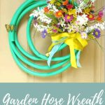 Garden house wreath with colorful faux flowers from the Dollar Store and yellow ribbon hanging on a tan door with text overlay that says garden hose wreath for summer