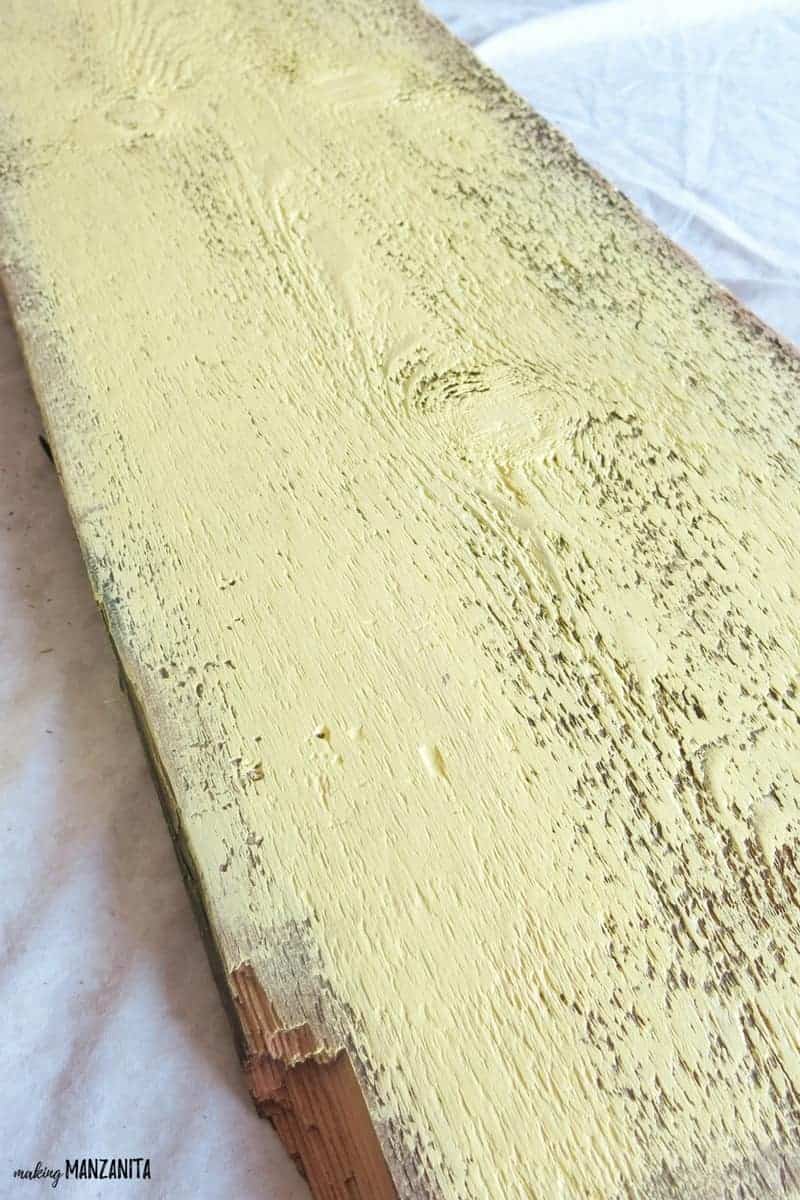 A close up look at the wood plank painted with a light sunshine yellow paint.