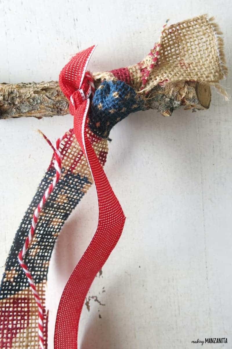 Pieces of burlap tied to a twig, making the beginning of an American flag window hanging