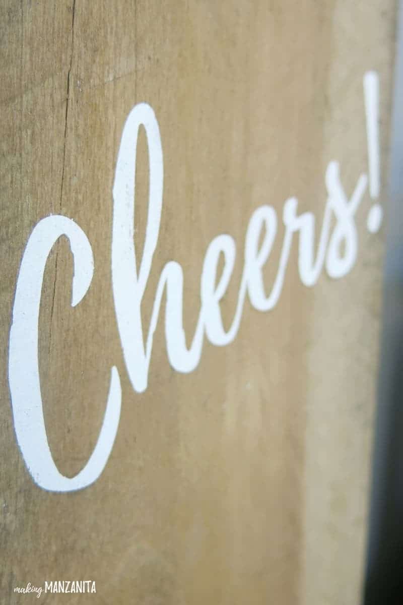 Zoomed in shot of Cheers in white lettering painted on reclaimed wood