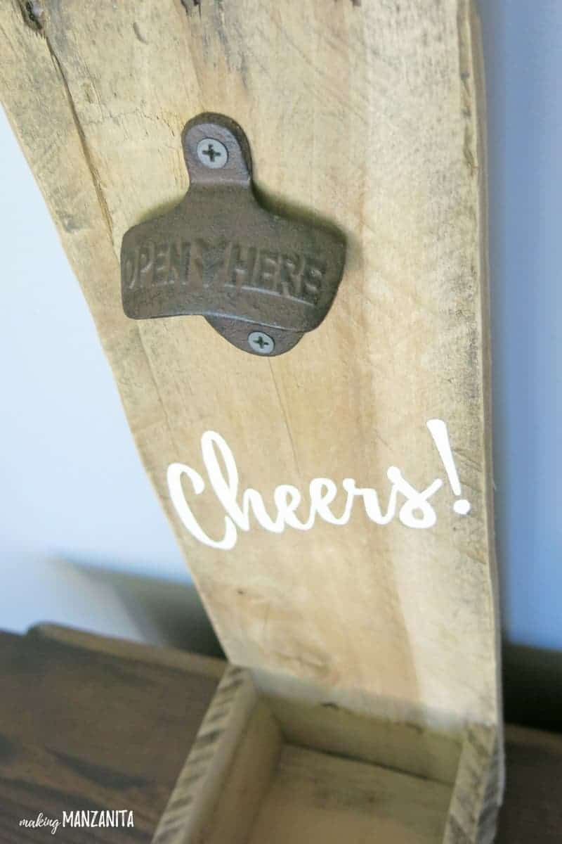 Gezoomt in Schuss von Palette Holz Flaschenöffner gemalt mit "Cheers" mit rustikalen Metall Opener