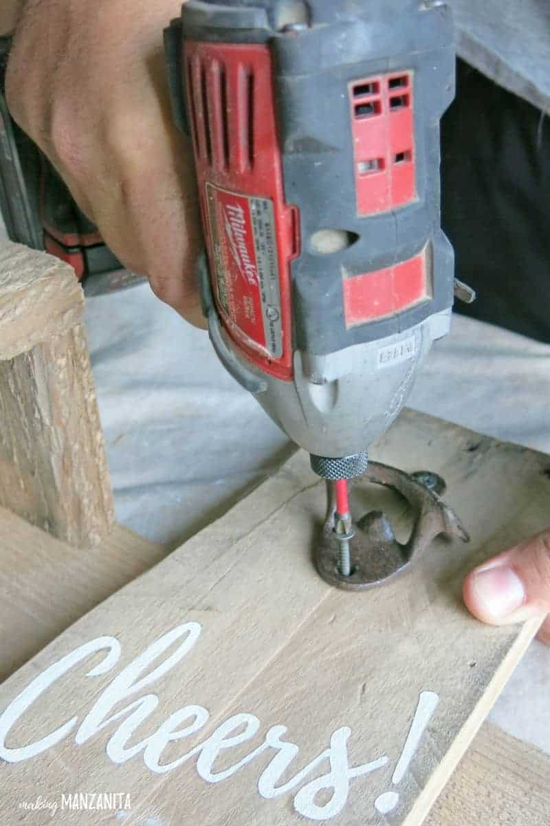 Bohren Flaschenöffner auf Holzstück, das mit Prost gemalt ist