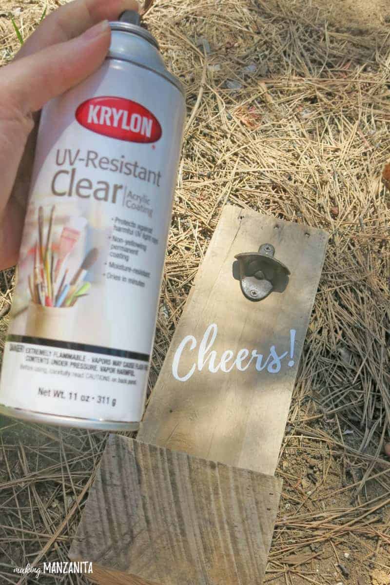 Spray bottle of Krylon UV-Resistant Clear acrylic coating in front of DIY bottle opener made with pallet wood and painted with Cheers on it 