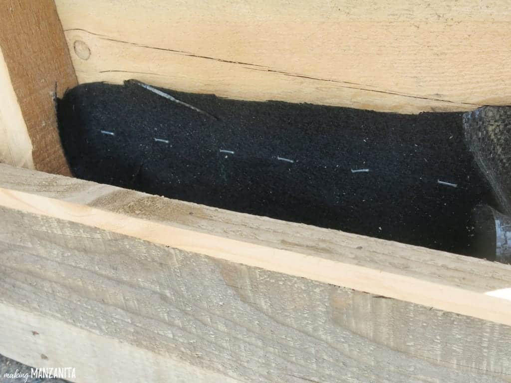 Strips of landscaping fabric stapled to the inside of a wooden pallet.