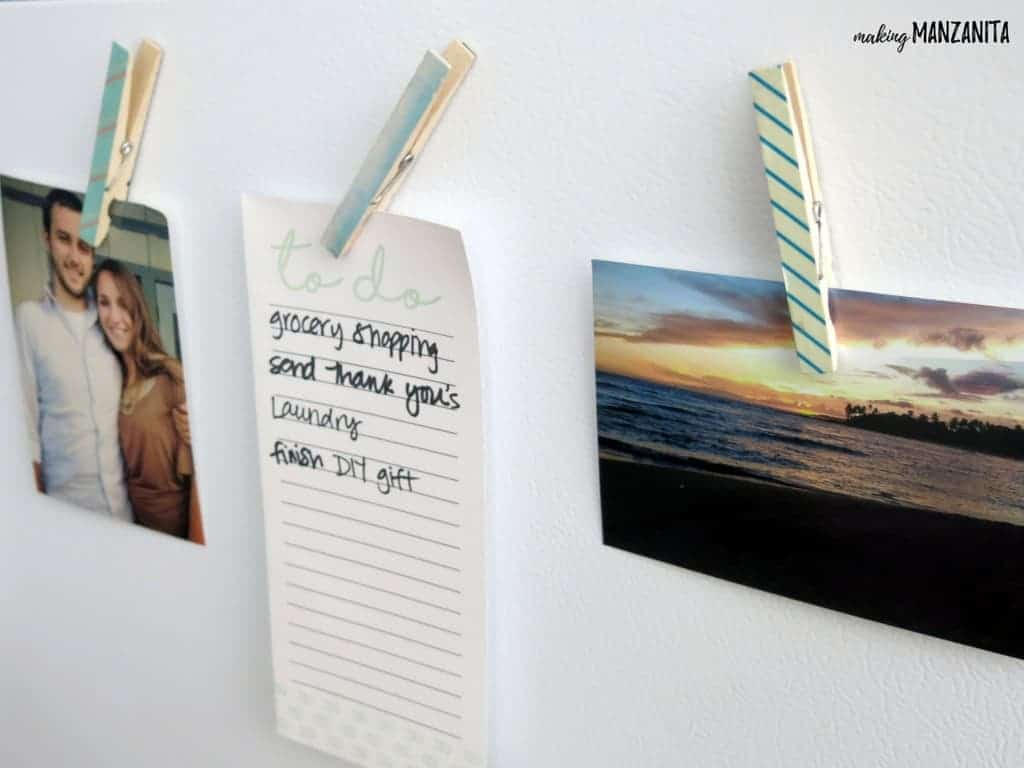 Three clothespin magnets hold pictures and a paper to do list to a white surface. Each clothespin is covered in a light blue colored washi tape.