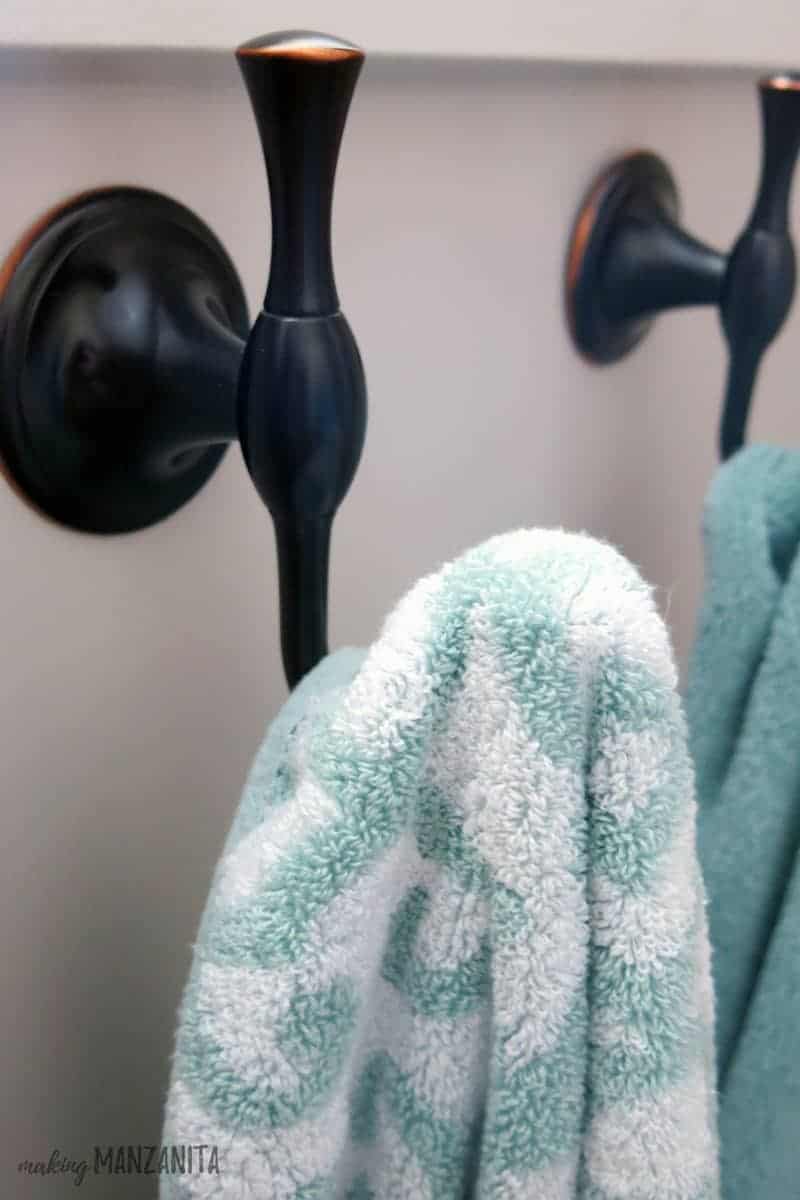 A close up look at the brass towel hooks mounted to the wall in our farmhouse master bathroom.