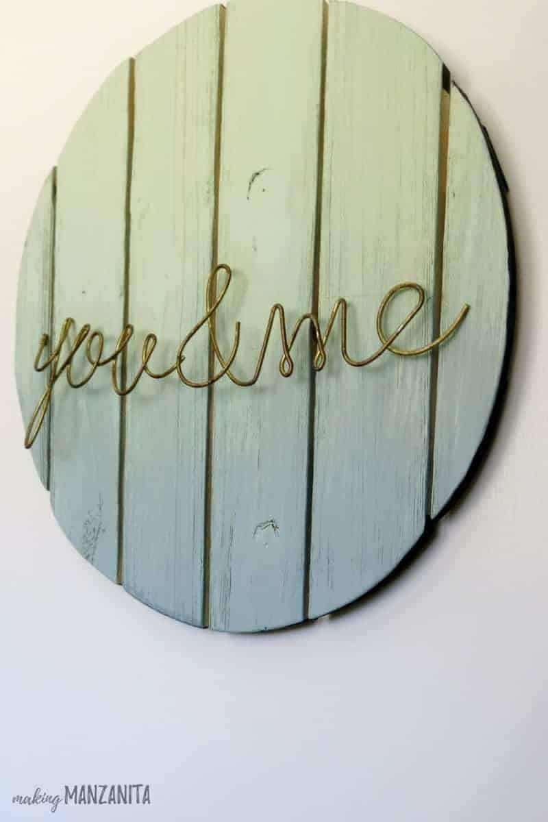 A round wood sign painted with ombre mint, and twisted wire that reads 