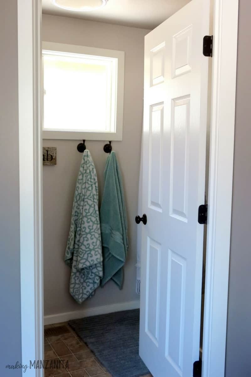 Our new farmhouse master bathroom - the white-painted door opens to two towels hanging on the wall.