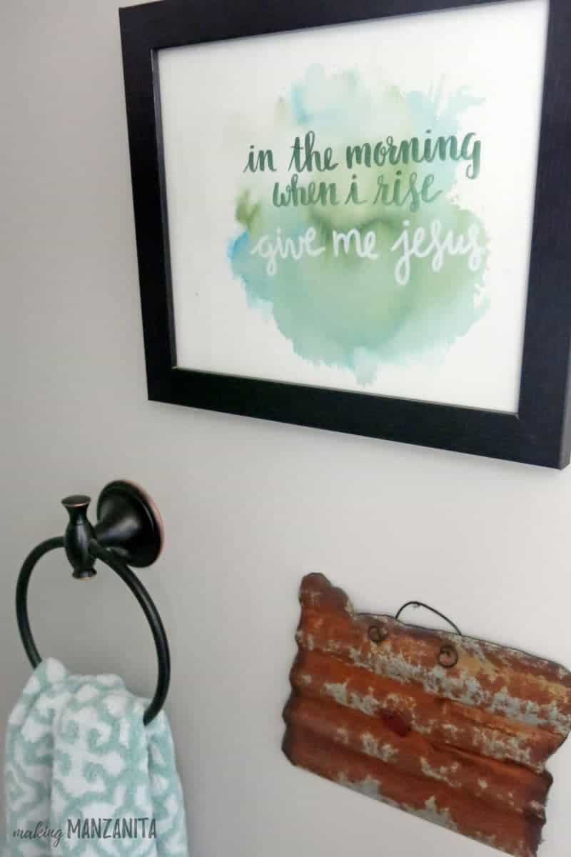 This lovely watercolor art hangs on the wall in our farmhouse master bathroom; it's a blue and green watercolor splash with the words 