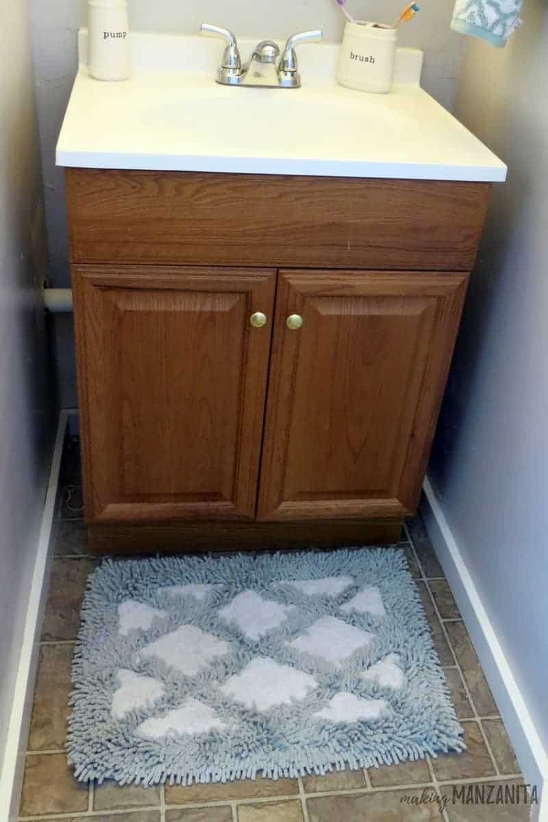 We made the most of this small cabinet and sink vanity in the master bathroom by adding a soap dispenser, a brush holder, and a blue and white diamond rug on the floor.