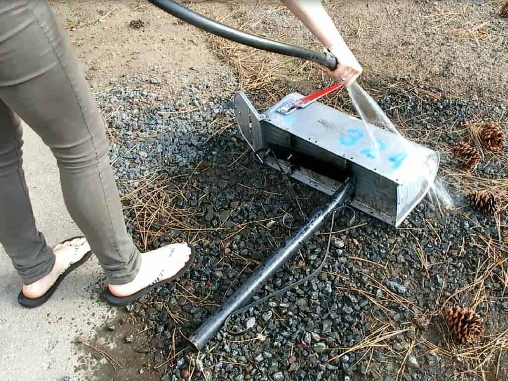 Woman cleaning and washing the old metal mailbox with hose