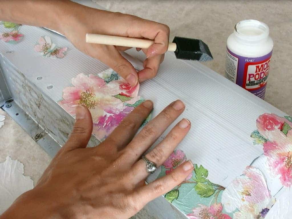 Attaching the cut flowers into the cleaned metal mailbox with mod podge