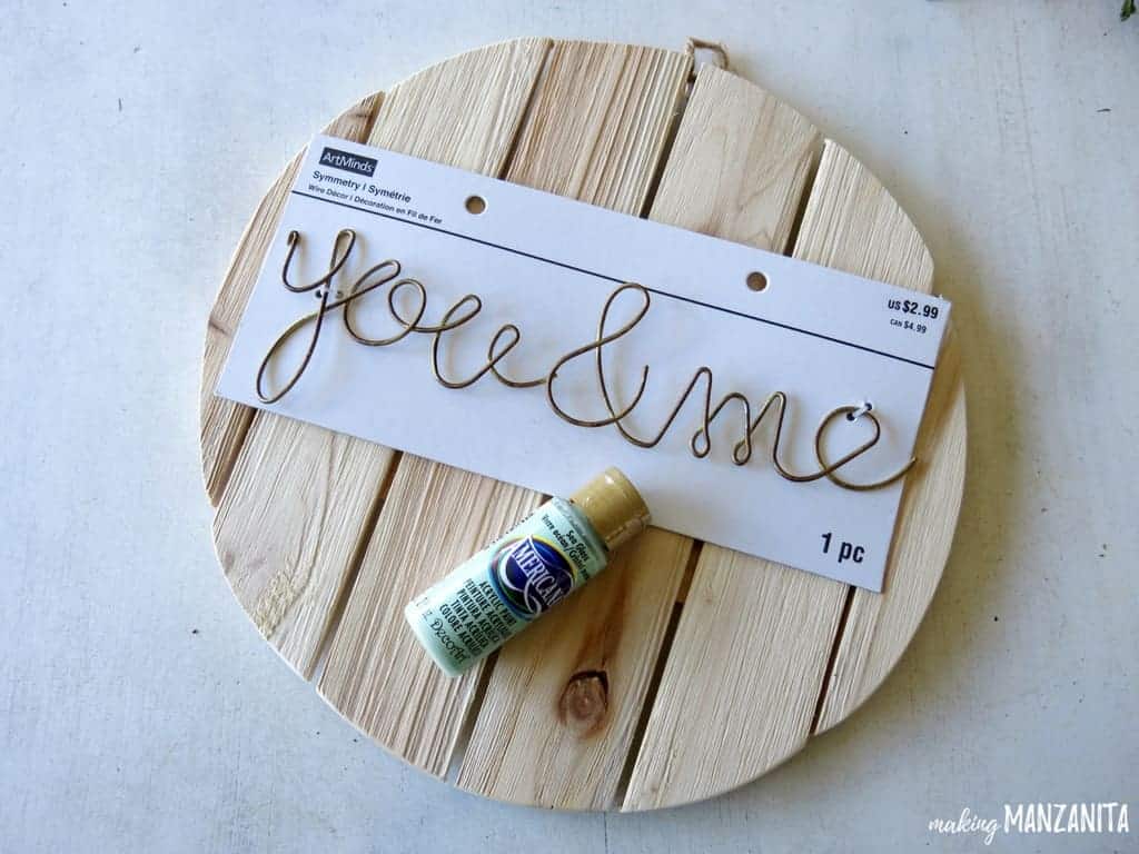 Supplies needed to make an ombre painted wood sign: a plain wood sign, decorative metal lettering that reads "you & me" and paint.