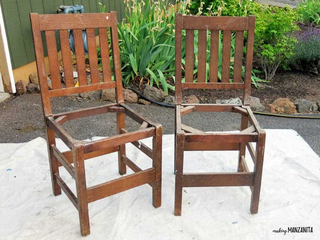 How to turn two chairs unto an upcycled backyard bench! Two dark stained wood chair frames with no cushions sit on a tarp in the backyard waiting to be upcycled.