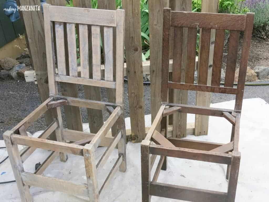 Two wood chairs sit side by side. The chair on the left has been sanded to remove the layer of dark wood stain. Sanding the chairs is the next step in upcycling these old wood chairs into a backyard bench