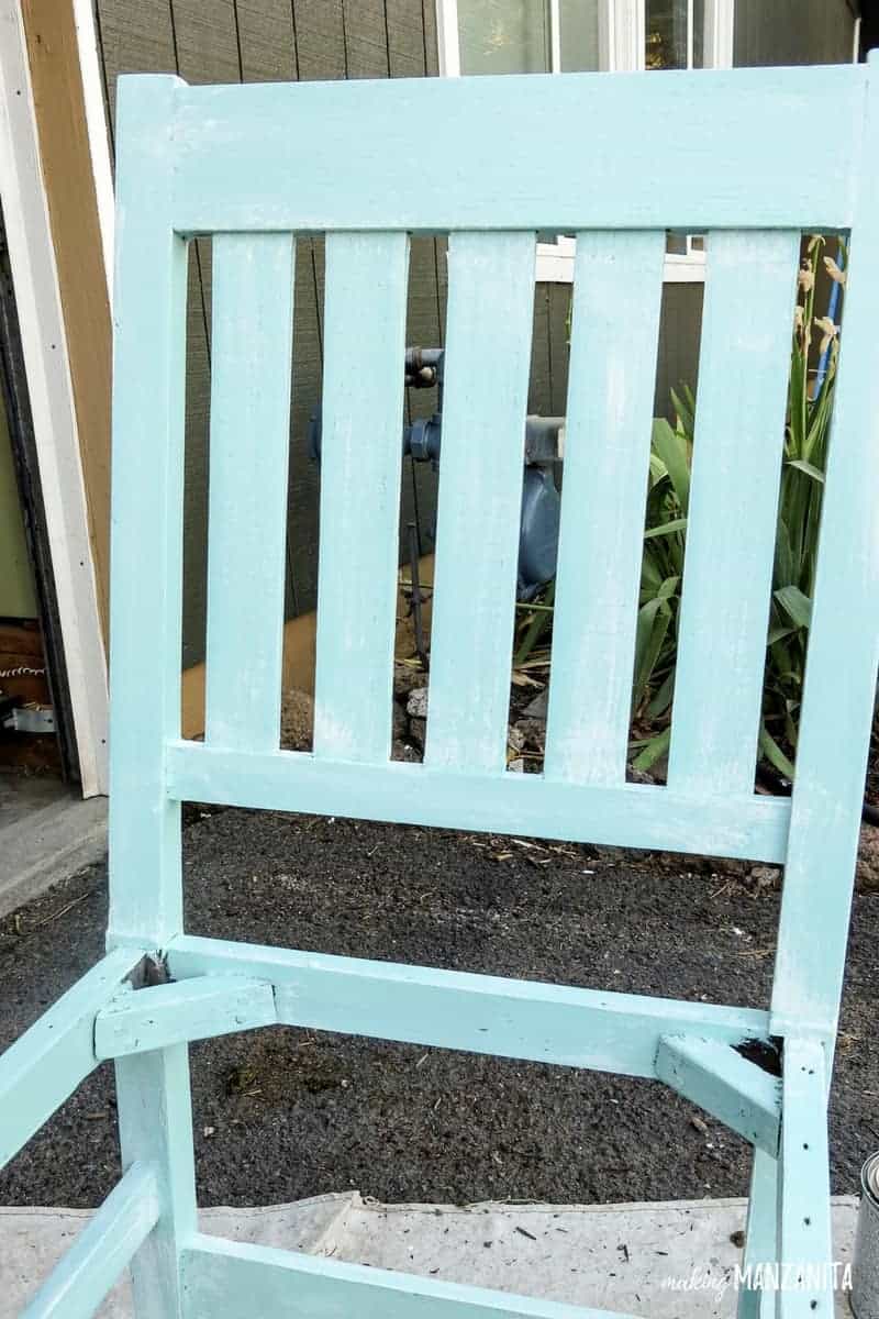 A fully painted upcycled chair is painted with Sherwin Williams Resilience Acrylic Latex Exterior Paint in the color Refresh, a light blue - and dry brushed with a soft while acrylic paint.