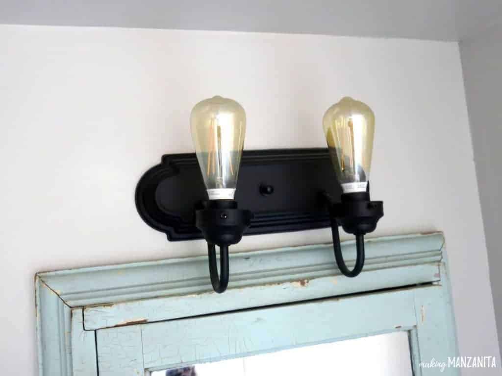 Ta da! Yes, it's really that simple to do a DIY bathroom light fixture makeover. All you need to do is give it a few coats of spray paint and add the old fashioned looking light bulbs.