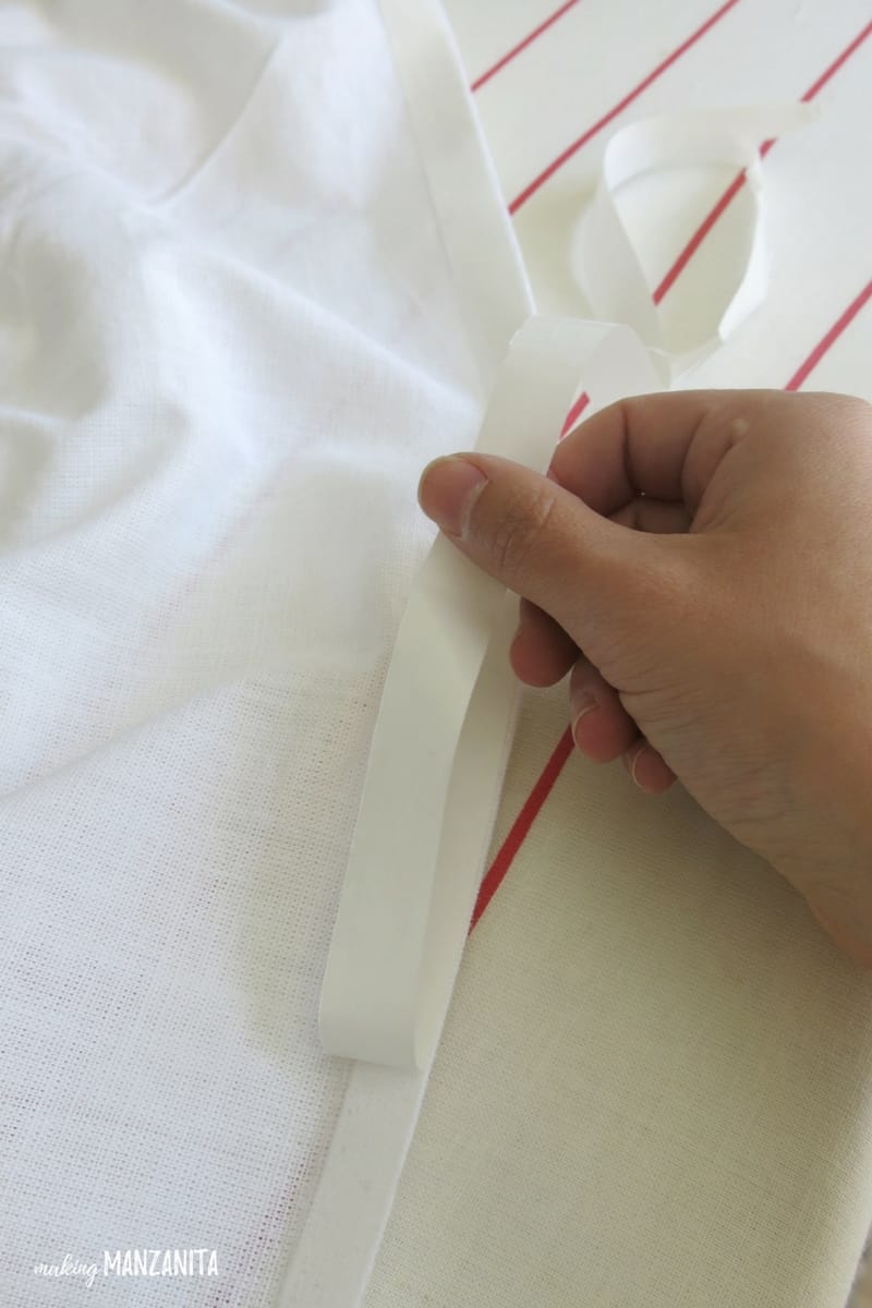 Peeling the protective backing off the no-sew adhesive tape that's been attached to a piece of fabric.
