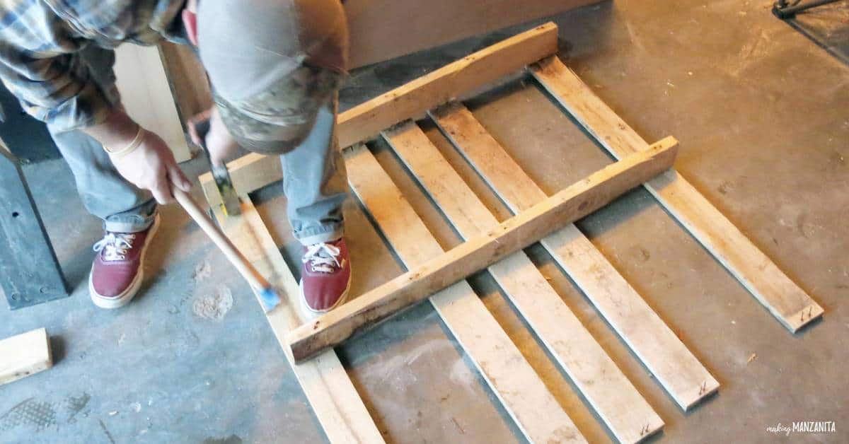 Using crow bar and hammer to take apart wood pallets to create a pallet wood side table