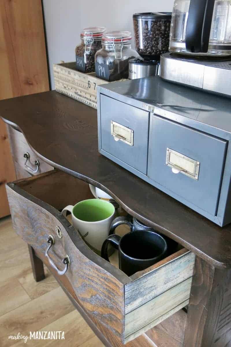 Dresser used as a coffee station with coffee makeover on top and coffee cups in the drawers with a top drawer open showing the colorful wallpapers on the sides of the dresser drawer