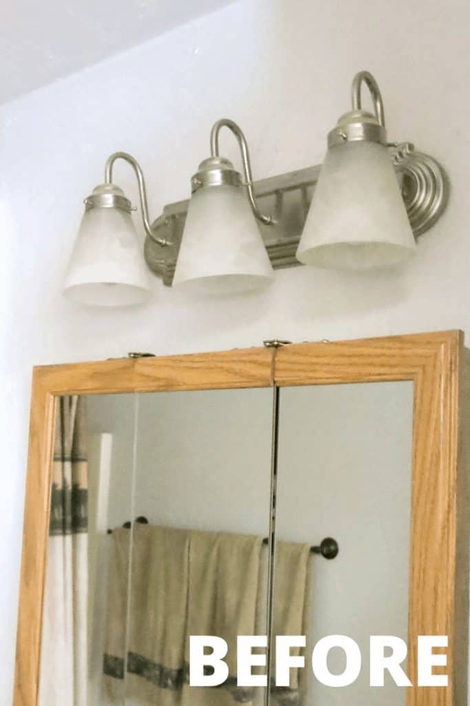 White and silver light fixture above the farmhouse vanity mirror before the spray paint light fixture makeover