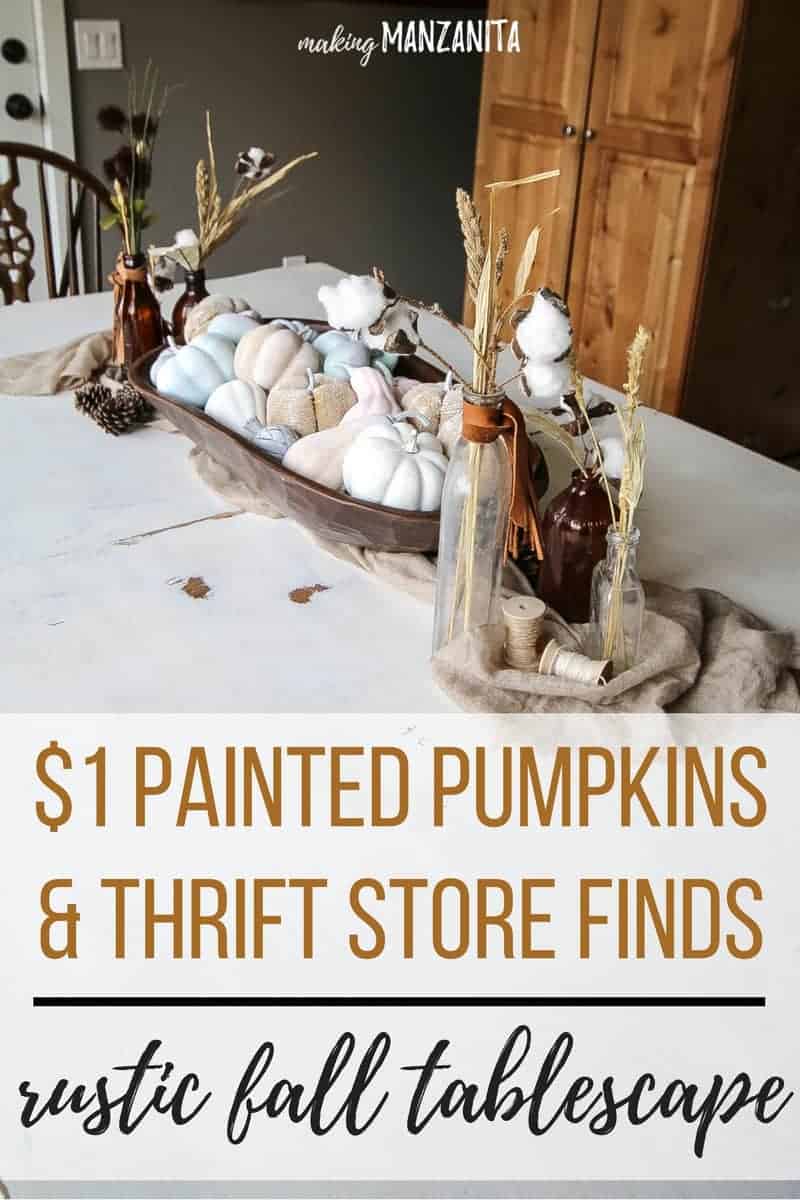 Fall tablescape with mini painted pumpkins in wooden dough bowl with vintage bottles holding dried wheat on white farmhouse table with text overlay that says  painted pumpkins and thrift store finds rustic fall tablescape