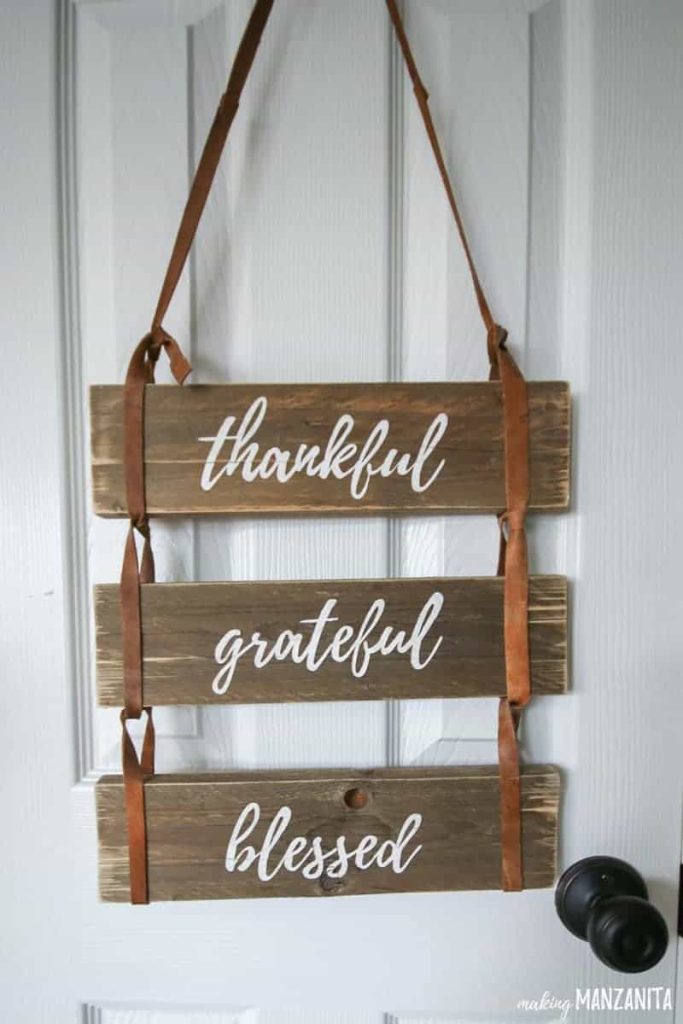 A close up view of a leather pallet sign, with the words "thankful grateful, blessed" painted on each of the three pallets.