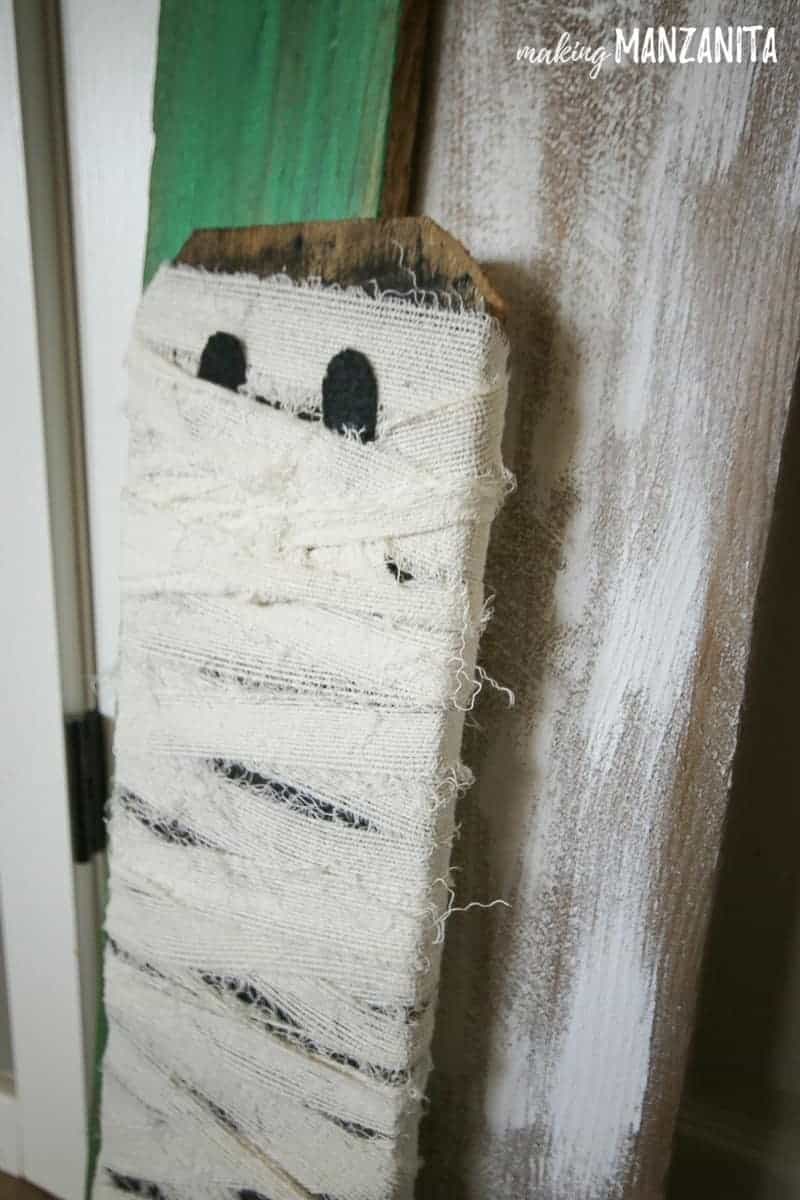 The most adorable little mummy decoration made from repurposed fence boards and white ripped fabric.