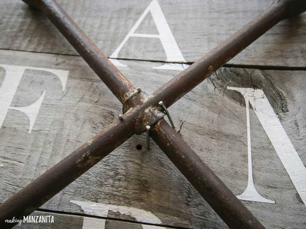 A close up look at how to attach the lug wrench to the wood FARM sign - using nails slightly bent inward to secure the lug wrench in place.