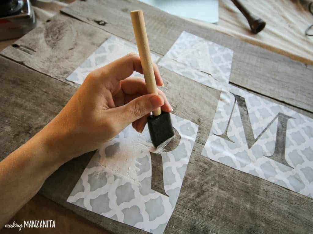 Using white craft paint and a sponge brush, paint over the FARM stencils on the wood farmhouse sign