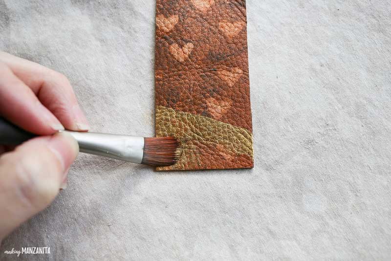 Decorating a diy leather bookmark with gold paint