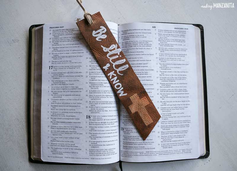 A homemade leather bookmark decorated with a cross and the words 'be still and know