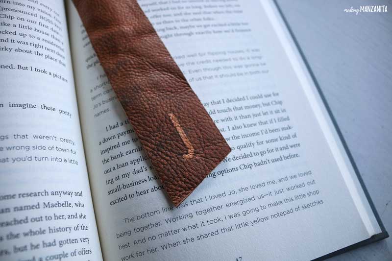 a diy leather bookmark decorated with the initial J laying across an open book