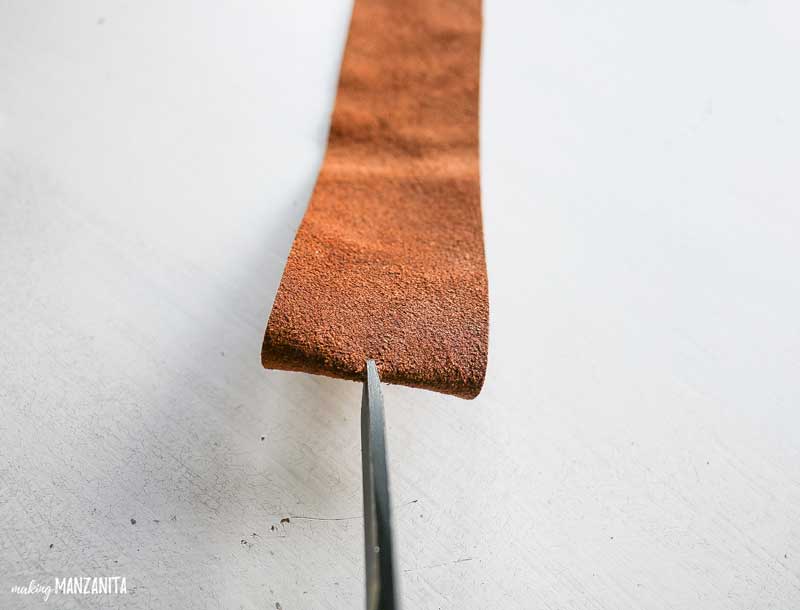 Adding a cut leather string to a hole at the top of the diy leather bookmark