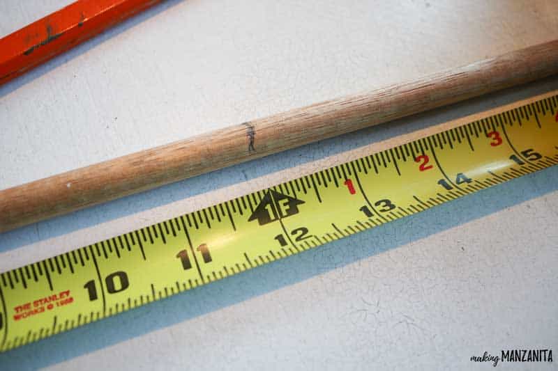 Measuring a wooden dowel and marking at 12 inches to make the center of mini Christmas tree with fabric tied