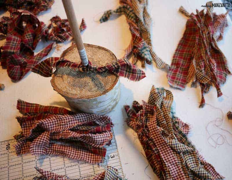 Homespun fabric strips and one strip tied to the wooden dowel for the fabric Christmas tree