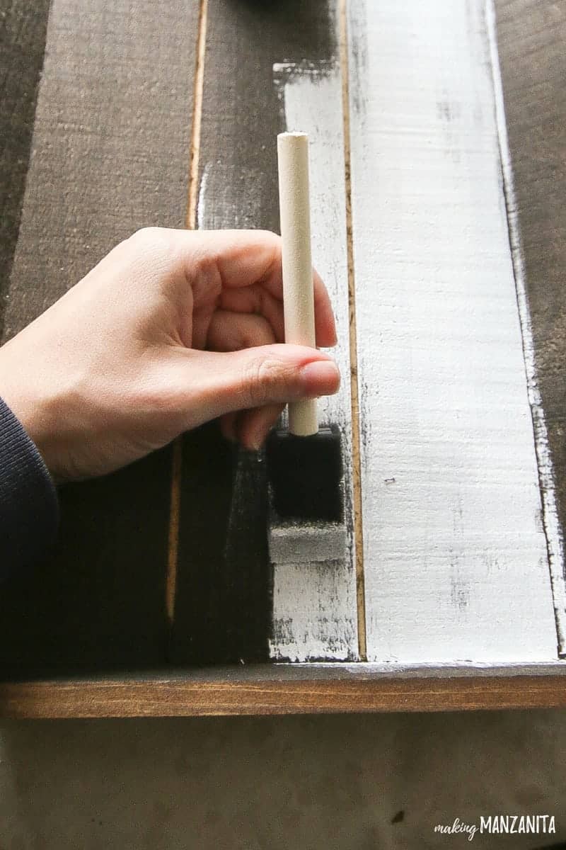 Hand holding a foam brush painting wood tray white over the stained surface